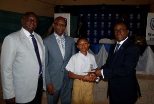 L-R: Principal, Ibadan Grammar School, (Senior Secondary), Mr. Oyeade Francis Ajani; Principal, Ibadan Grammar School, (Junior Secondary), Mr. Samuel Ojo Jinadu; Master Peter Abayo, being presented a prize by Chief Executive, Stanbic IBTC Bank, Dr. Demola Sogunle, during the Financial Literacy Day in Ibadan on Thursday 15 March, 2018.